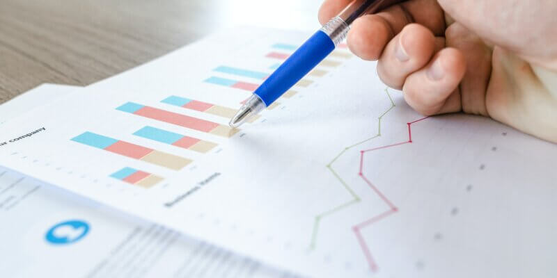 how to track churn rate for a business - hand holding pen above paper showing charts and graphs