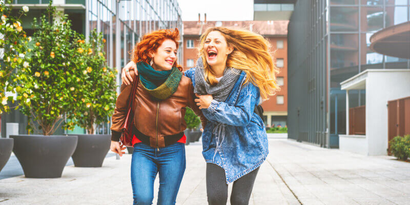 if you want to make a friend, let them do you a favor - two women laughing and walking together